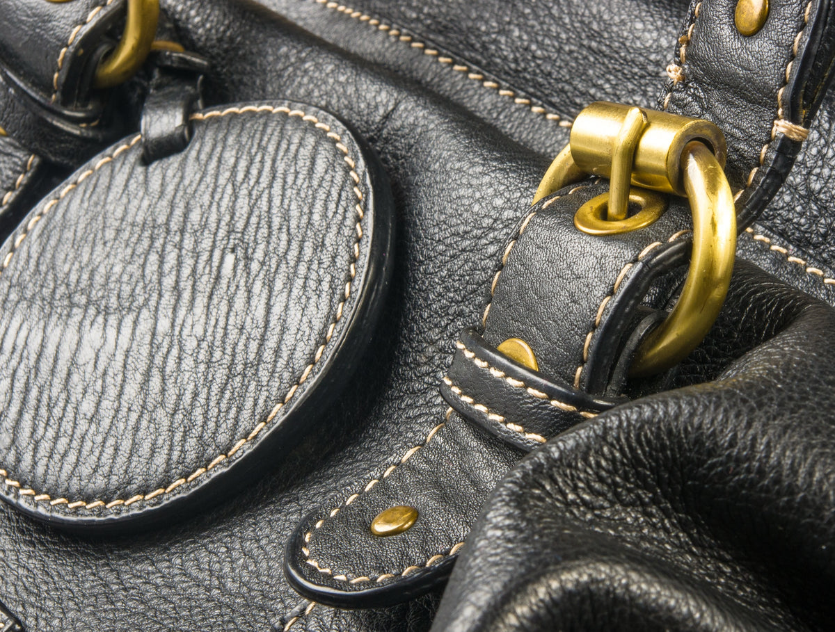 Dettaglio borsa in pelle nera con finiture oro - ARY Luxury